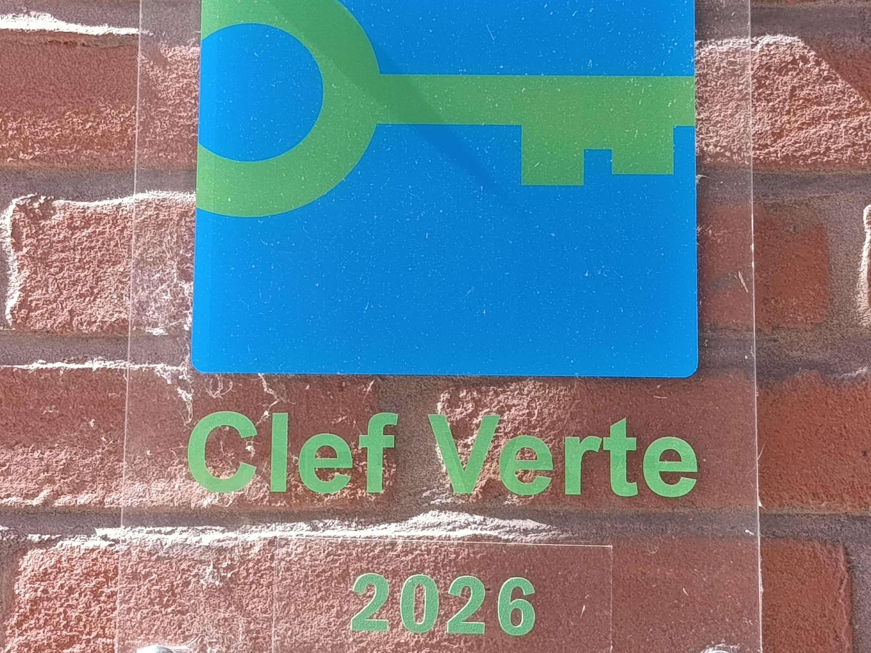A sign with a key symbol and the text 'Clef Verte 2026' on a brick wall.