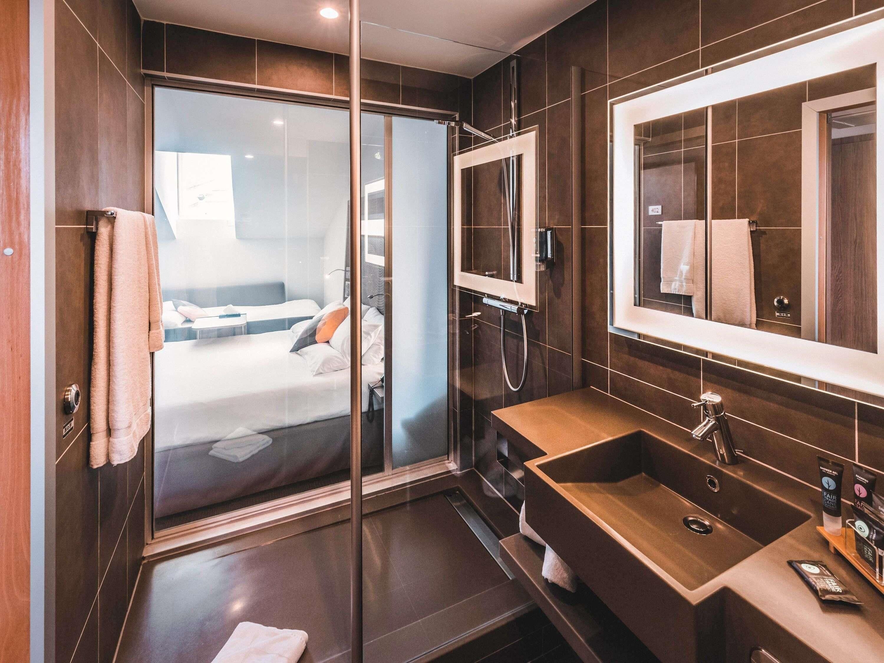 Une salle de bain moderne avec une douche à parois de verre, un meuble-lavabo en bois et un grand miroir.