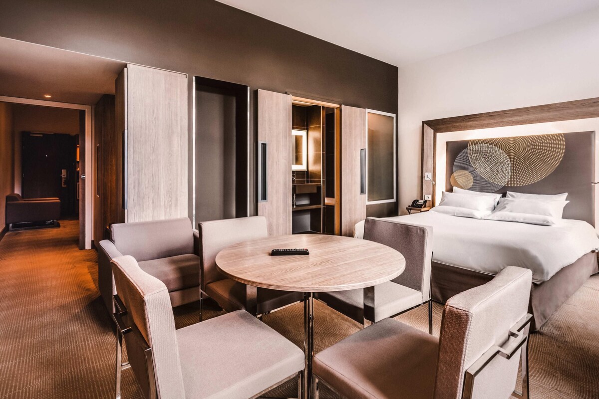 Ein Hotelzimmer mit einem Bett, einem runden Tisch und einer Sitzecke mit Stühlen.