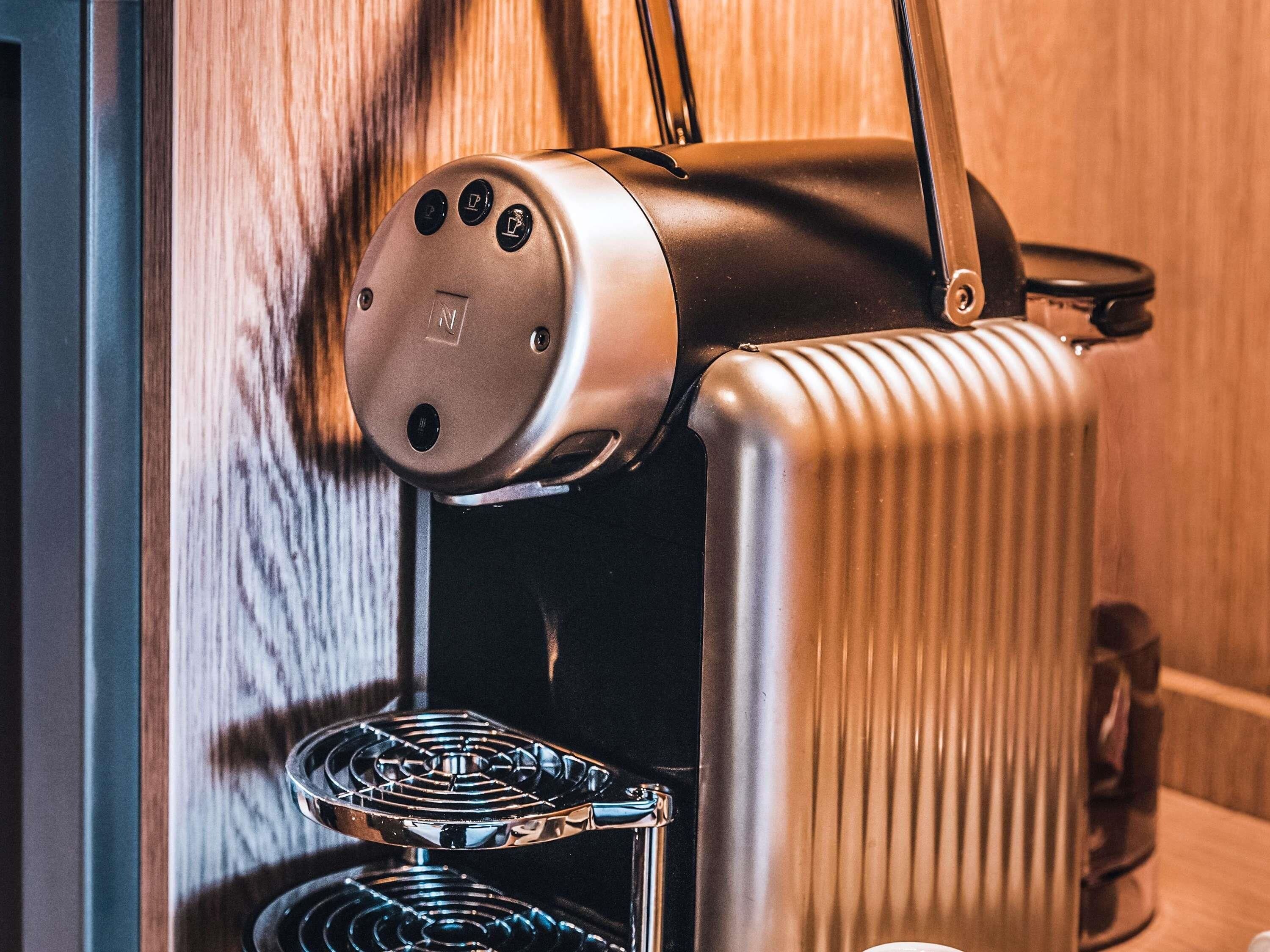 A kitchen with a built-in espresso machine, a kettle, and a stovetop.