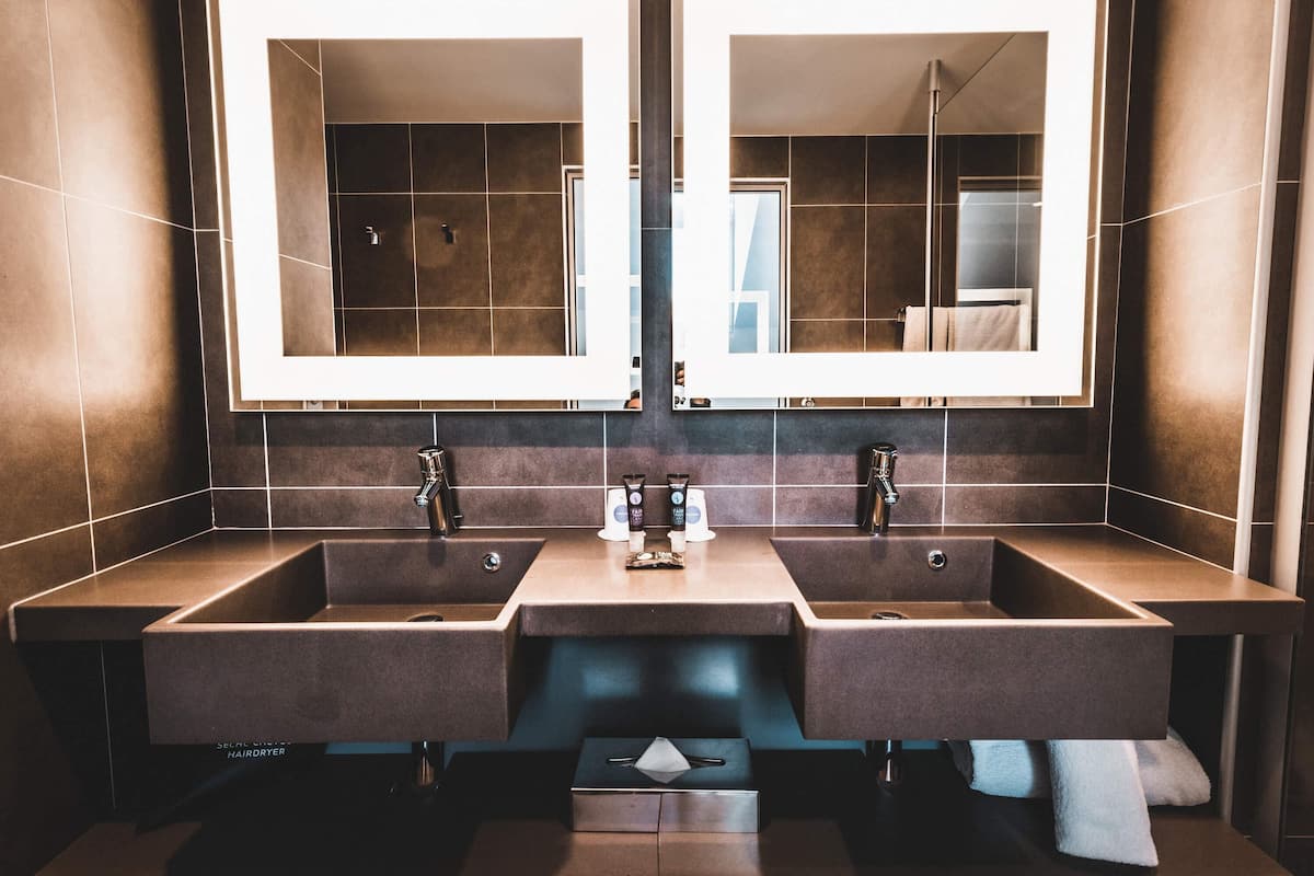 A modern bathroom with two sinks, large mirrors, and a hairdryer.