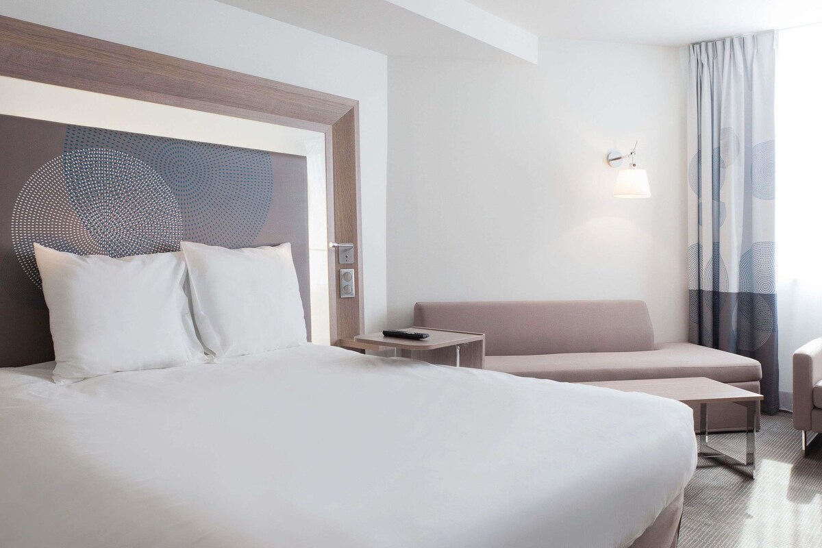 Ein Hotelzimmer mit einem großen Bett, einer Couch, einem kleinen Tisch und einer Wandleuchte.