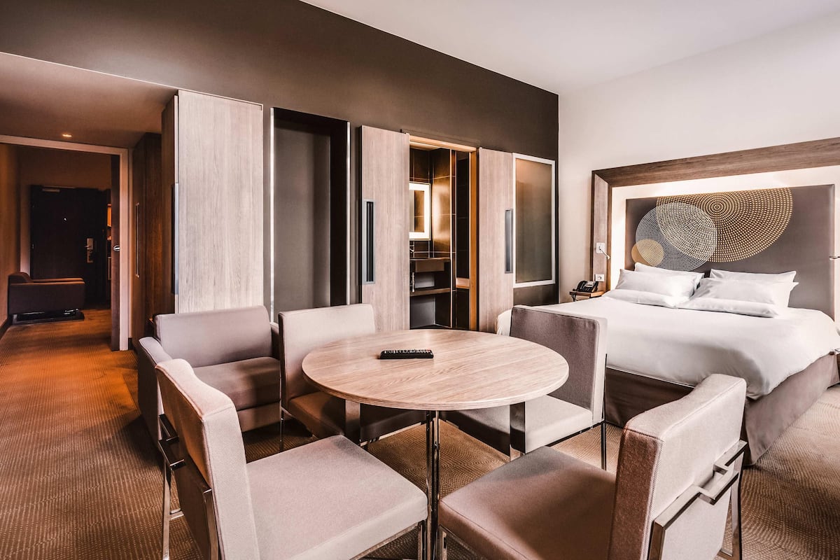 Een hotelkamer met een bed, een ronde tafel en een zithoek met stoelen.