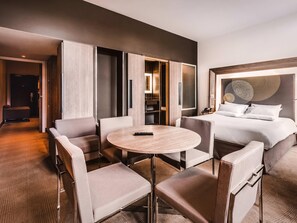 A hotel room with a bed, a round table, and a seating area with chairs. - Novotel Toulouse Centre Wilson (Toulouse)
