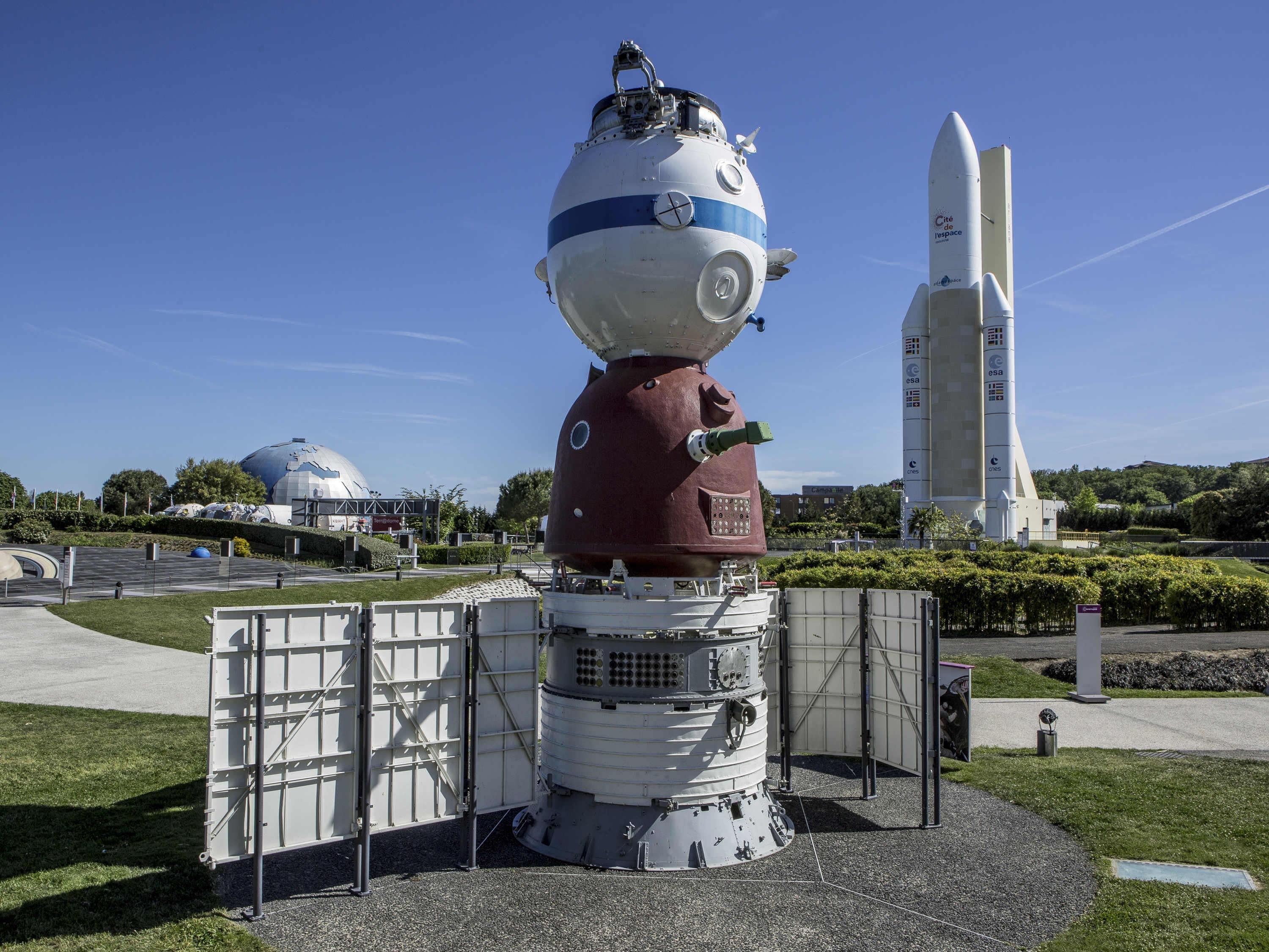A space exhibit with a large spherical structure, a rocket, and a dome-shaped building in the background.