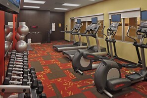 Ein Fitnessstudio mit Laufbändern, Crosstrainern und Kurzhanteln.