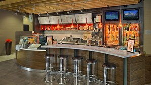 Un espace bar moderne doté d’un comptoir incurvé, de plusieurs tabourets et d’un éclairage suspendu.