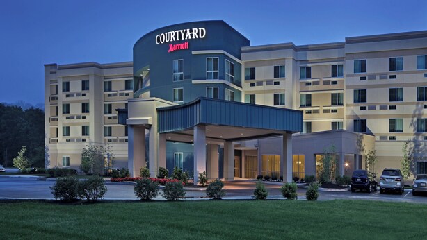 Un hôtel Courtyard Marriott au design moderne, avec plusieurs étages et un hall d’entrée abrité.