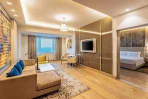 A modern hotel room with a sofa, armchair, and a bed.