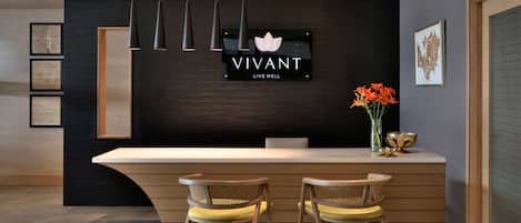 Un área de recepción con una pared oscura, un logo y un cartel que dice