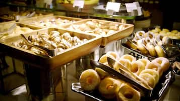 A buffet with various food items, including pastries and desserts, arranged in trays.