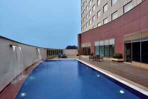 Un edificio moderno con piscina, asientos exteriores y fachada roja.