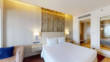 A hotel room with a large bed, two bedside tables with lamps, a wall-mounted decorative panel, and a large mirror.