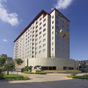 Un hotel Radisson moderno de gran altura, con un acceso destacado y un patio ajardinado.