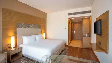 Habitación de hotel moderna con una cama grande, lámparas de noche, un televisor de pantalla plana y una mesa de centro de vidrio.