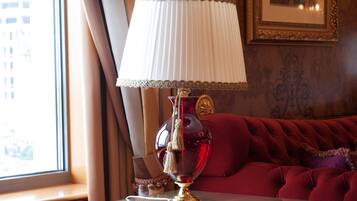 A room with a red sofa, a glass table with a red lamp, and a window with curtains.