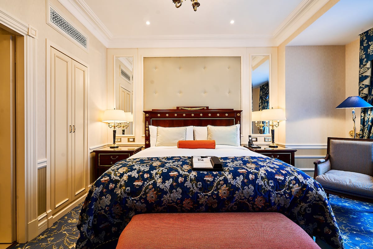 A hotel room with a large bed, two bedside tables, a chair, and a mirror.
