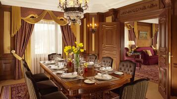 A formal dining room with a long table set for a meal, surrounded by upholstered chairs.