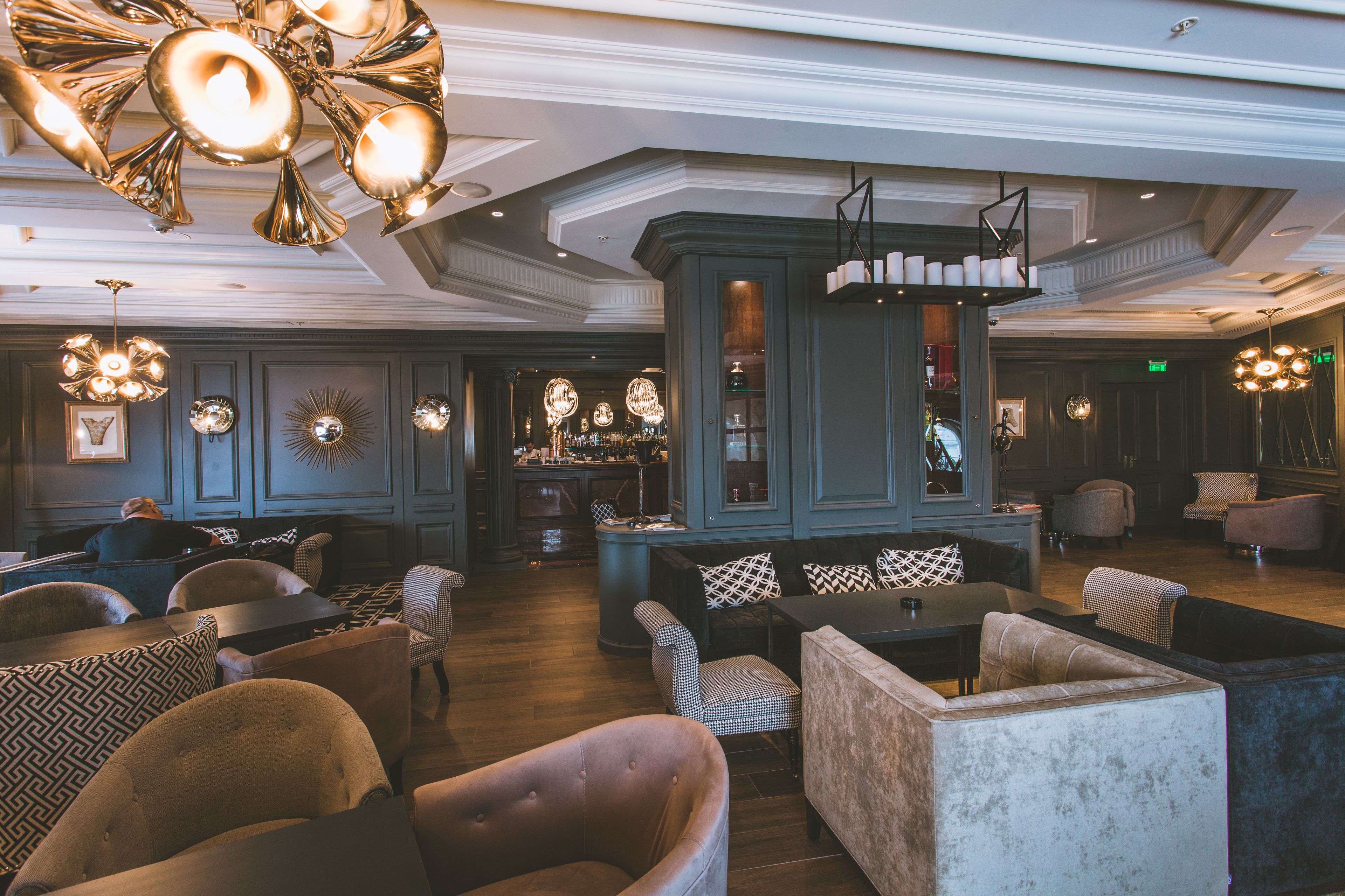 Um hall amplo com área de bar, sofás e luminárias decorativas.