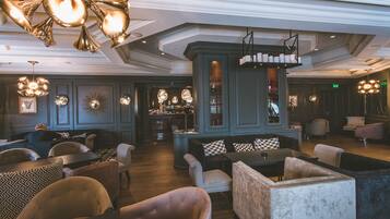 Um hall amplo com área de bar, sofás e luminárias decorativas.