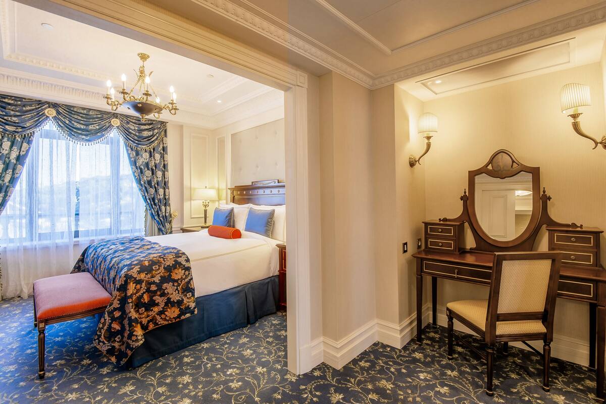 A hotel room with a bed, a dresser, a chair, and a large mirror.