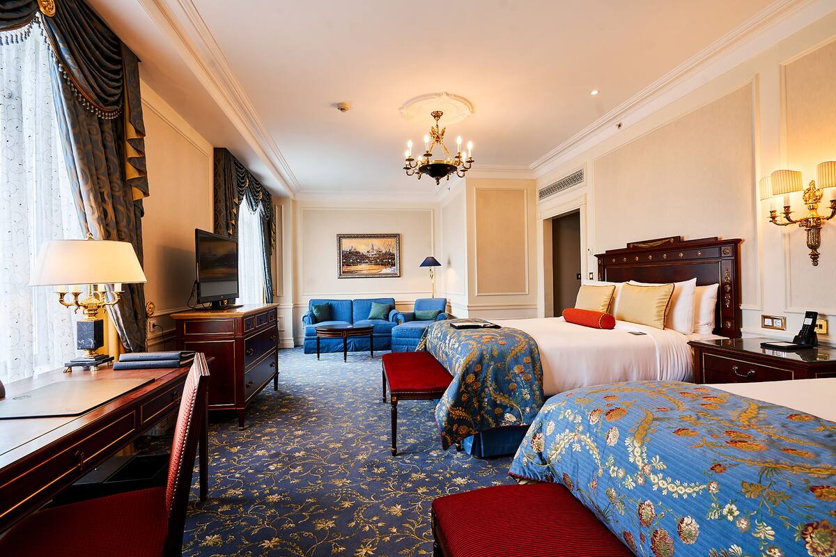 A hotel room with a large bed, a sofa, a desk, and a TV.