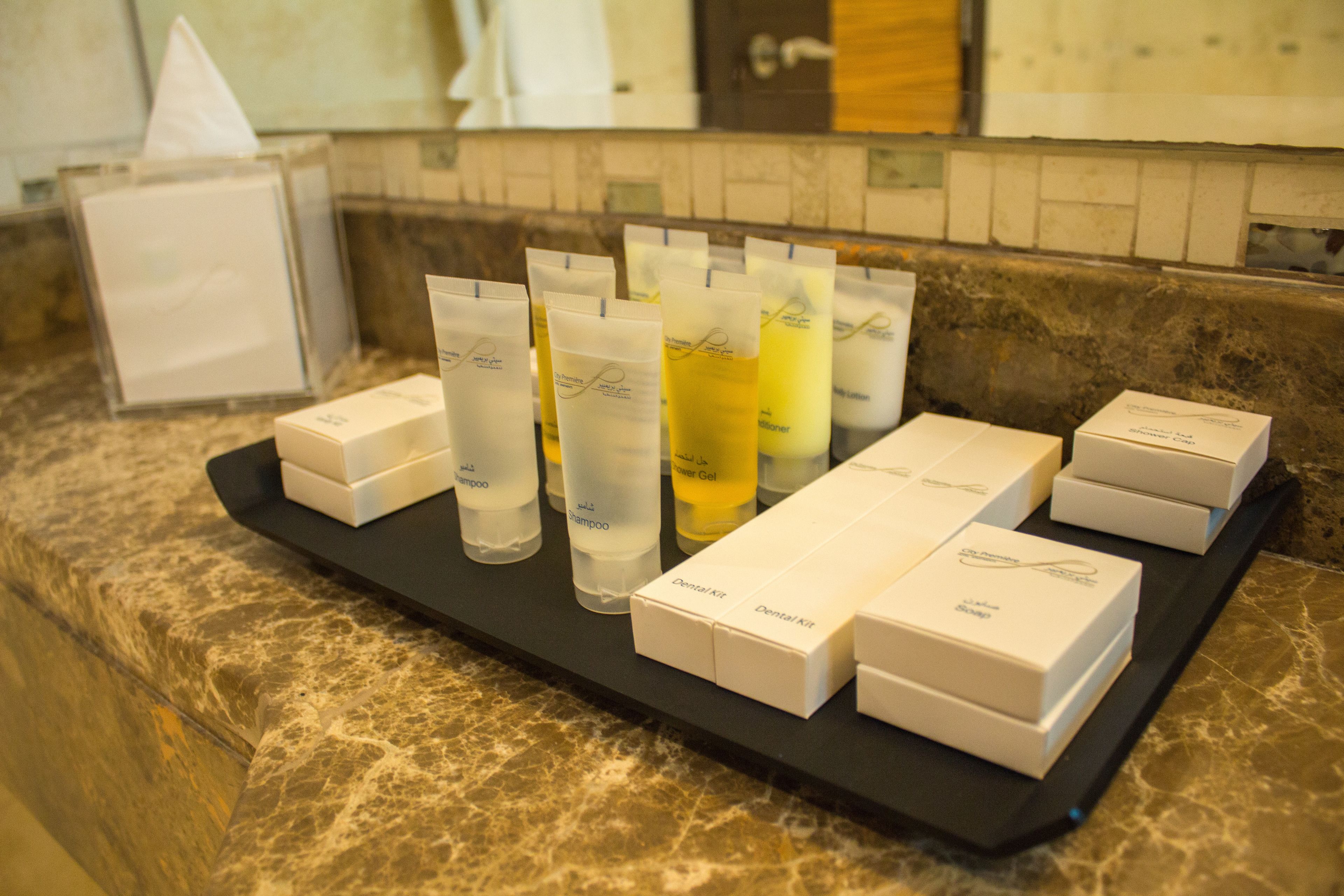 Een dienblad met toiletartikelen, zoals shampoo, conditioner en een tandverzorgingsset, op een marmeren aanrecht.