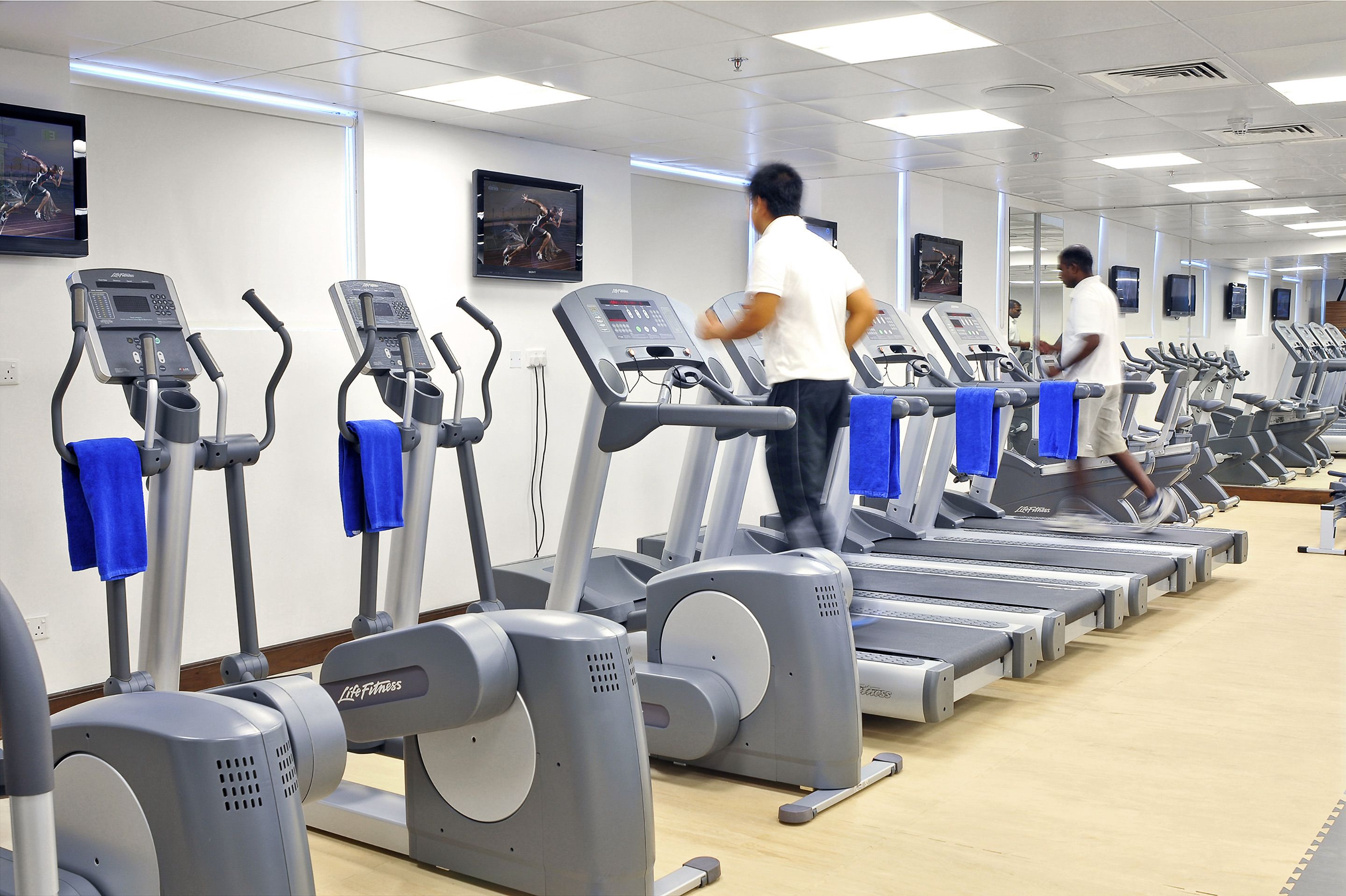 Un gimnasio con varias cintas de correr y equipo de ejercicio.