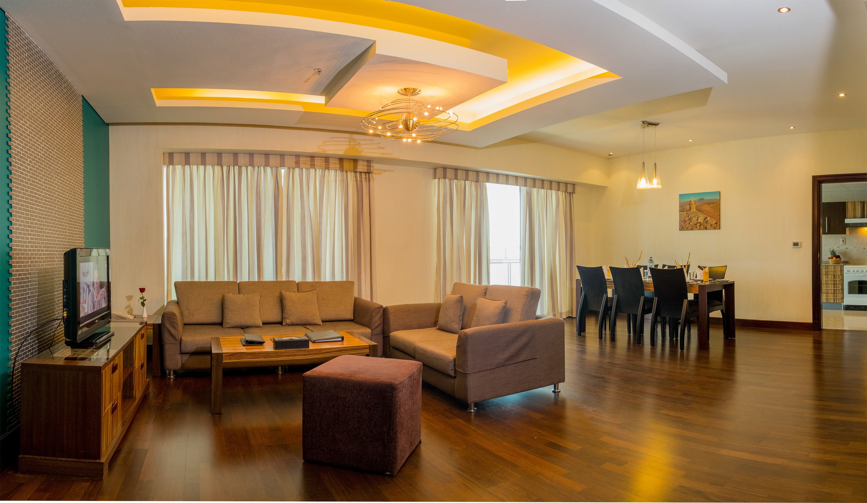 Una sala de estar moderna con sofá, reposapiés y un comedor con sillas y mesa.