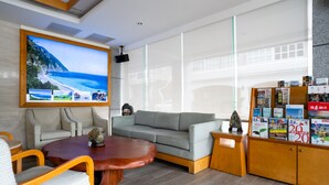 A modern living room with a grey sofa, a wooden coffee table, and a bookshelf filled with magazines. - Hotel Ocean (Hualien City)