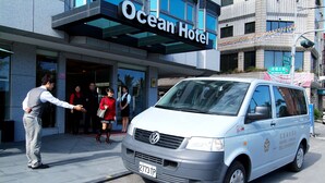 A white van with the text "HOTEL OCEAN" and a phone number parked in front of a building with a sign reading "Ocean Hotel". - Hotel Ocean (Hualien City)