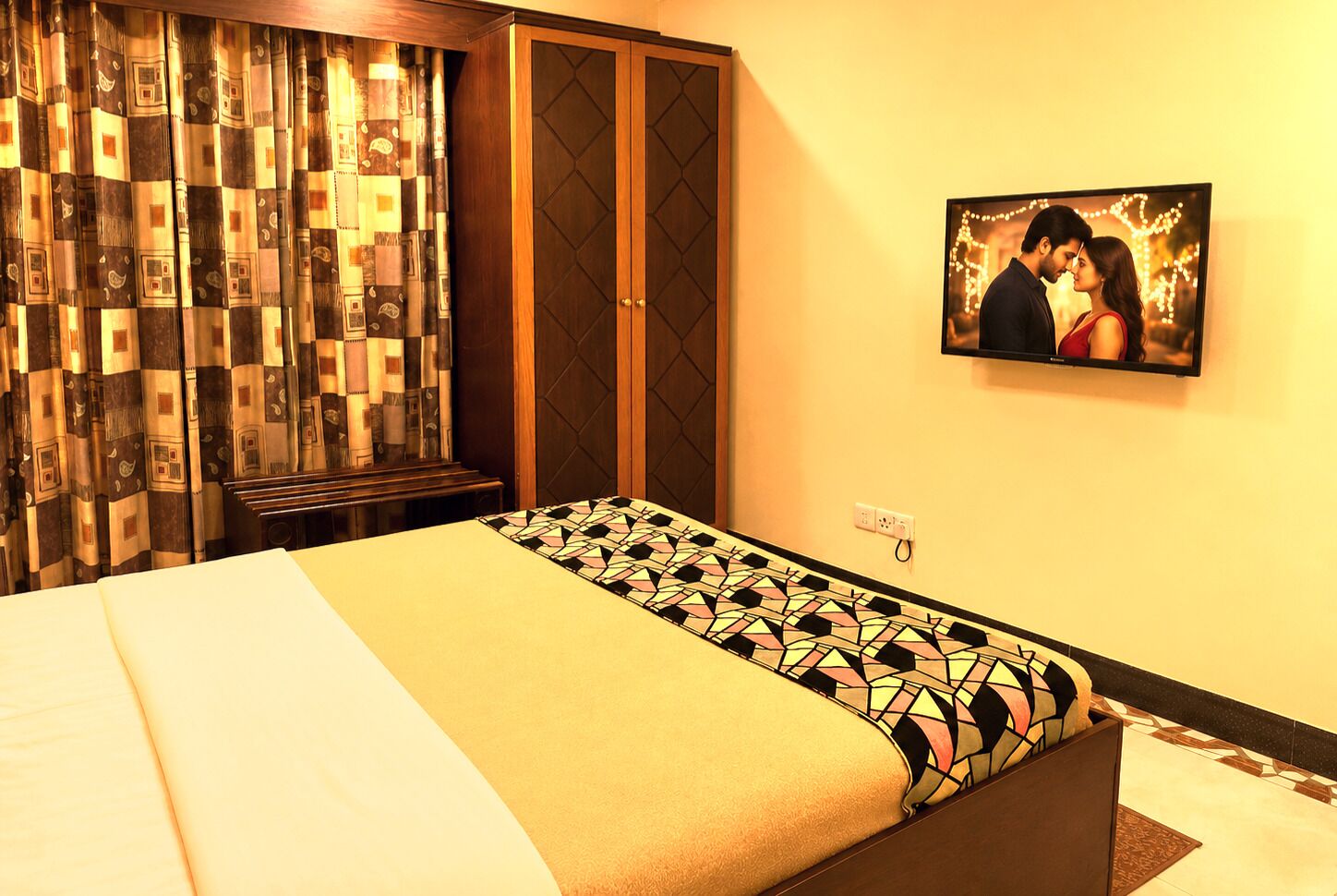 A hotel room with a bed, a television, and a patterned curtain.