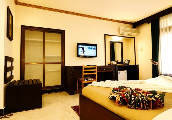 A hotel room with a bed, a desk, a chair, a television, and a large window with curtains. - New Dodoma Hotel (Dodoma)