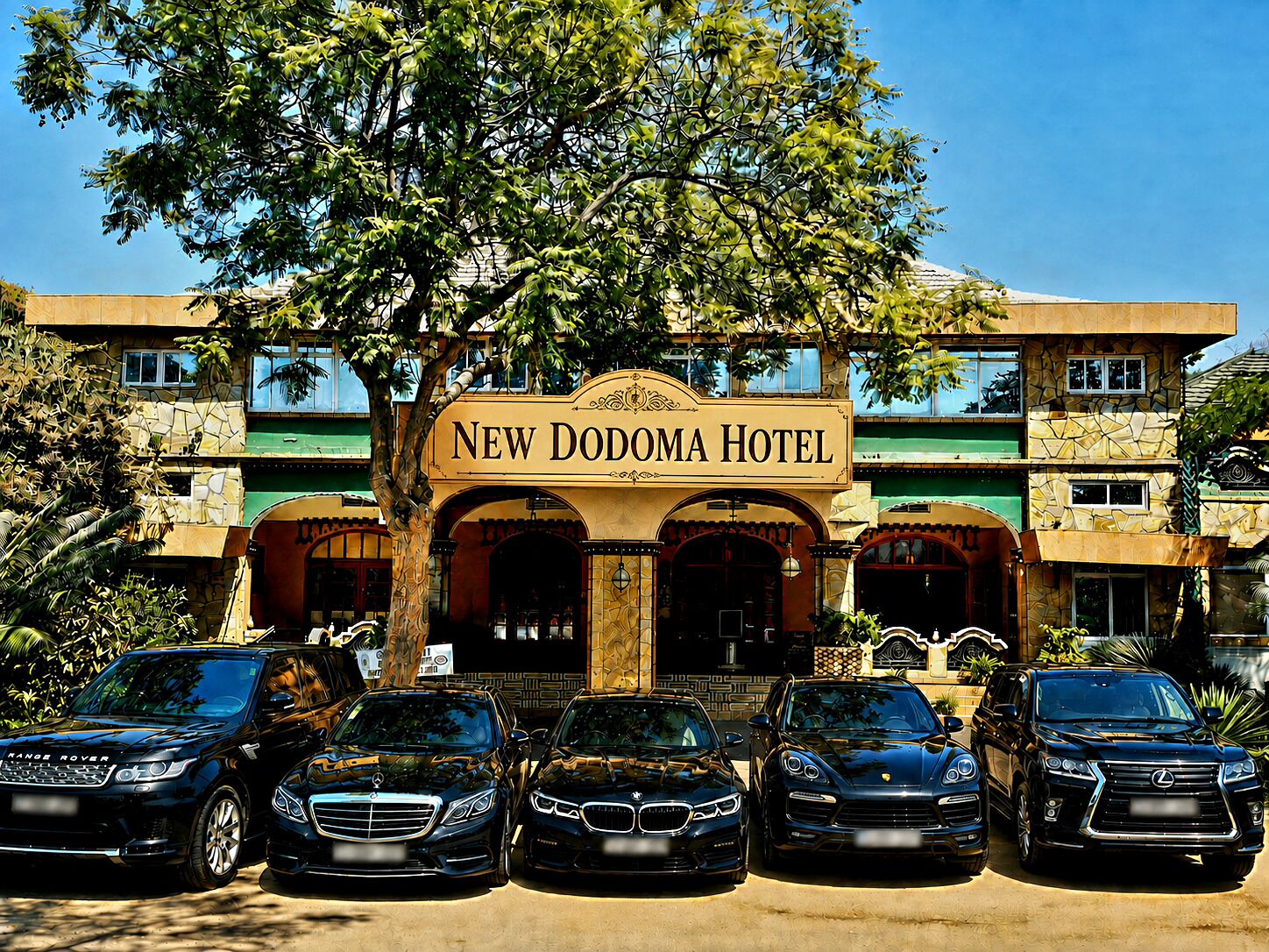 La façade du nouvel hôtel Dodoma, avec son panneau indicateur, ses nombreuses entrées et les voitures de luxe garées devant.