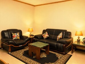 A living room with a sofa set, two side tables with lamps, a coffee table, and a patterned rug.
