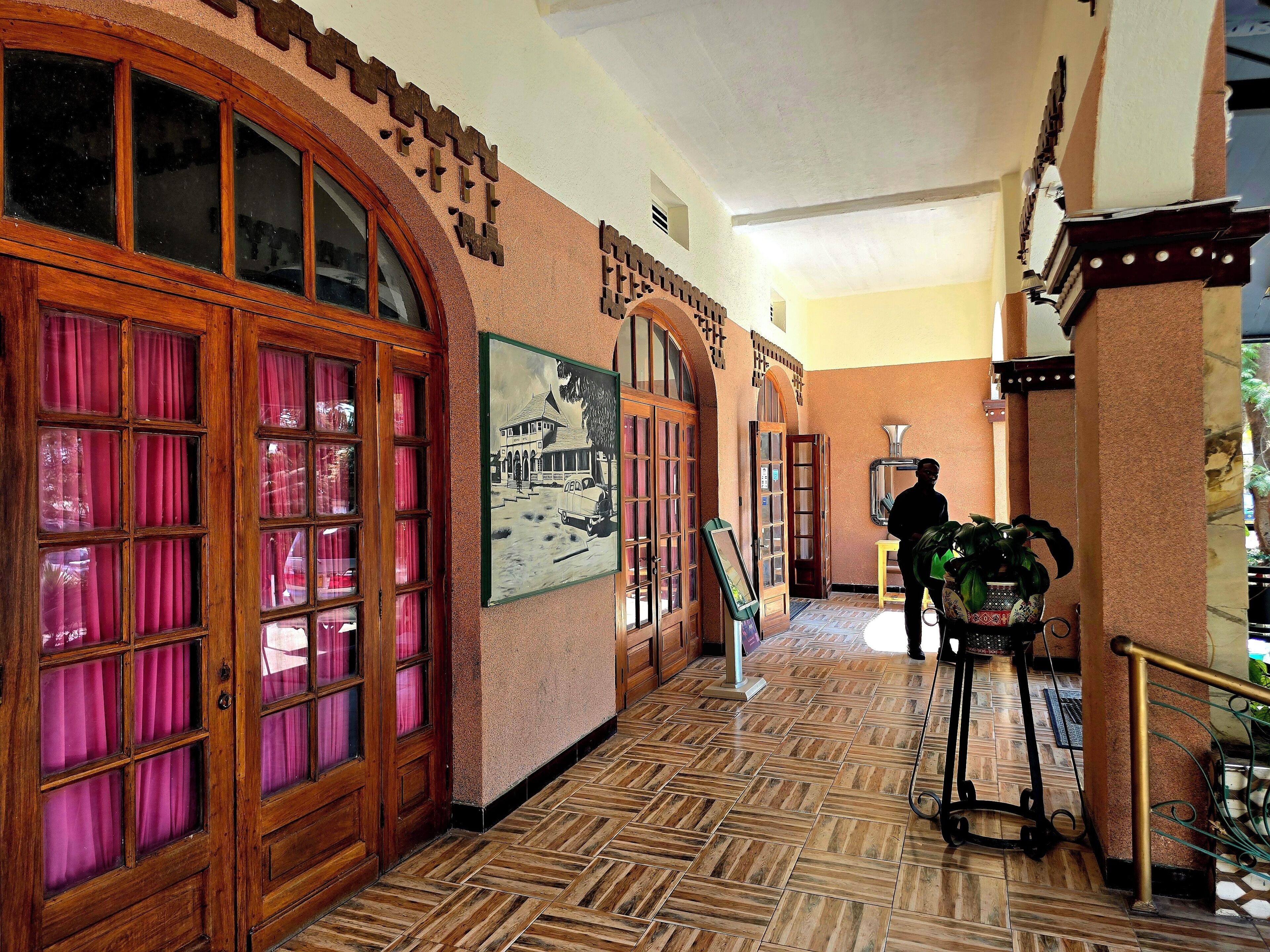 A hallway with wooden doors, a tiled floor, and a framed picture on the wall.