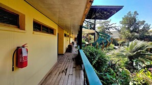 A covered outdoor area with a wooden deck, a fire extinguisher mounted on the wall, and a spiral staircase leading to an upper level. - New Dodoma Hotel (Dodoma)