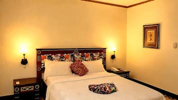 A hotel room with a bed, bedside lamps, a nightstand, a framed picture on the wall, and a decorative item on the bed.