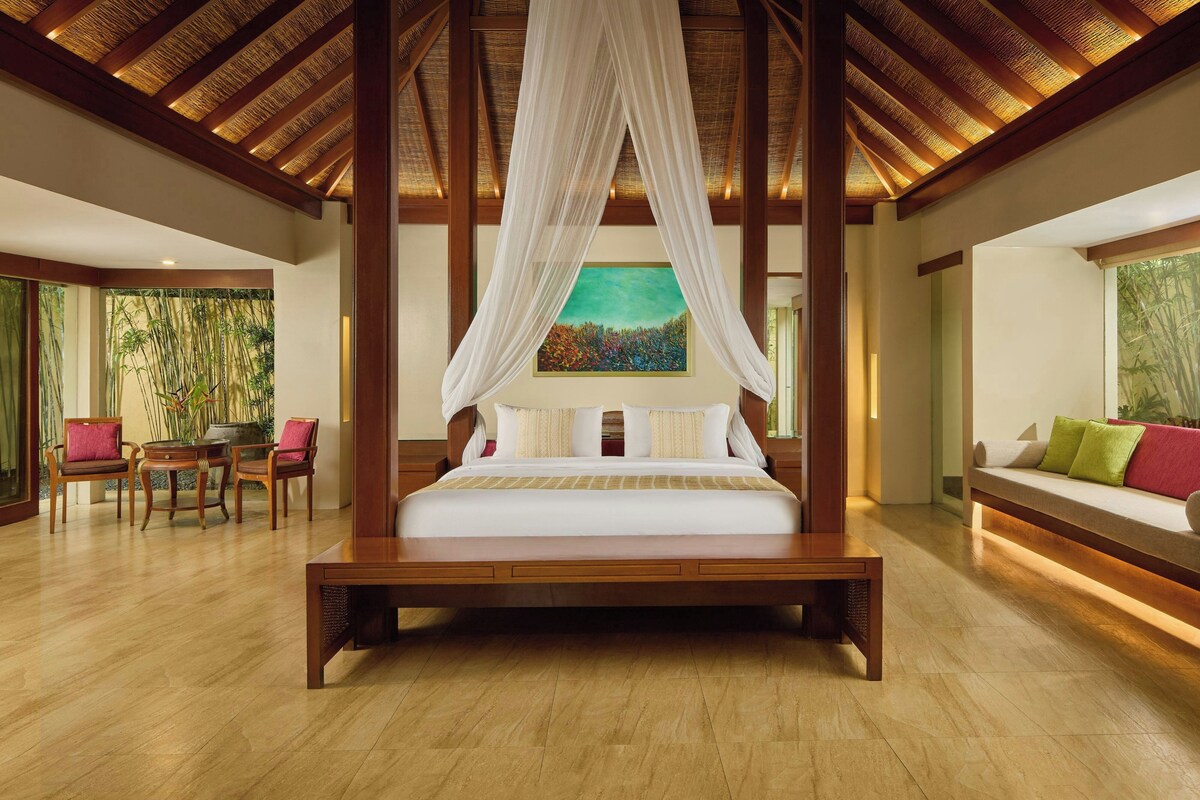Un dormitorio amplio con una cama grande, vigas de madera en el techo y vistas al bambú.