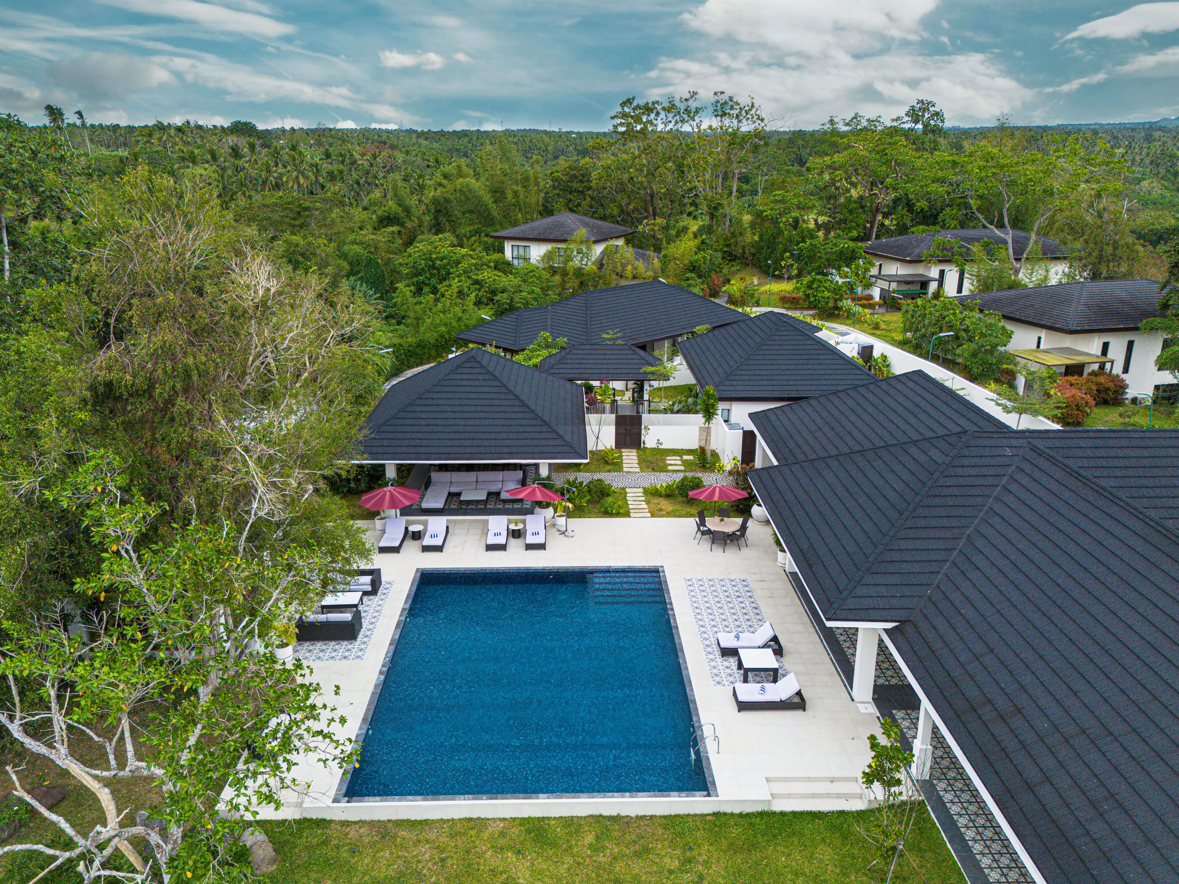 A resort with a swimming pool, lounge chairs, and umbrellas.
