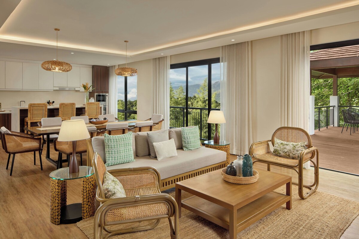 A spacious living area with a sofa, chairs, a dining table, and a kitchen in the background.