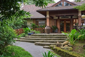 Un edificio con un letrero que dice "ALIVE! VEGAN RESTAURANT" y una escalera que lleva a la entrada.