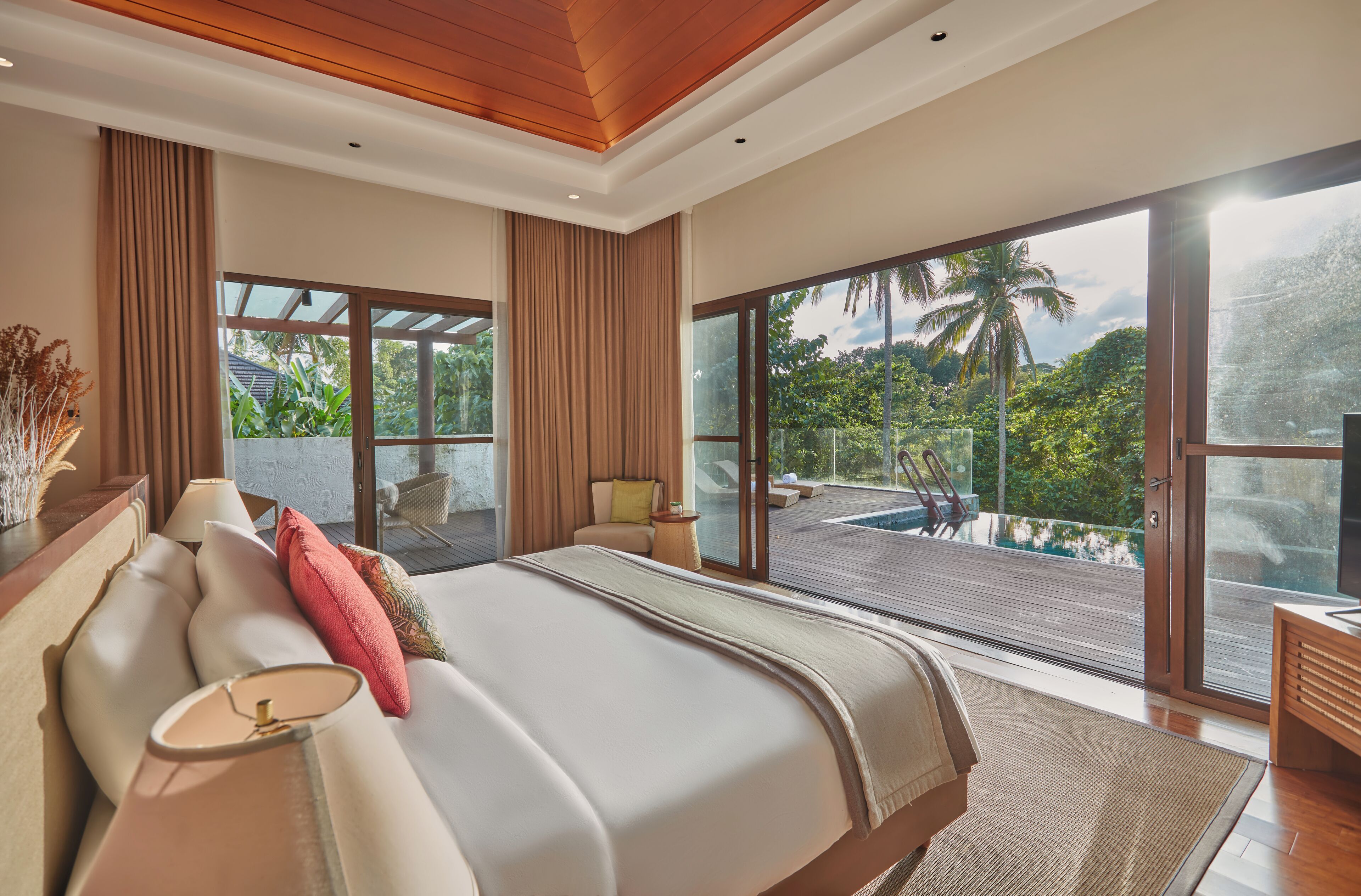 A modern bedroom with a large bed, a view of a pool, and a balcony.