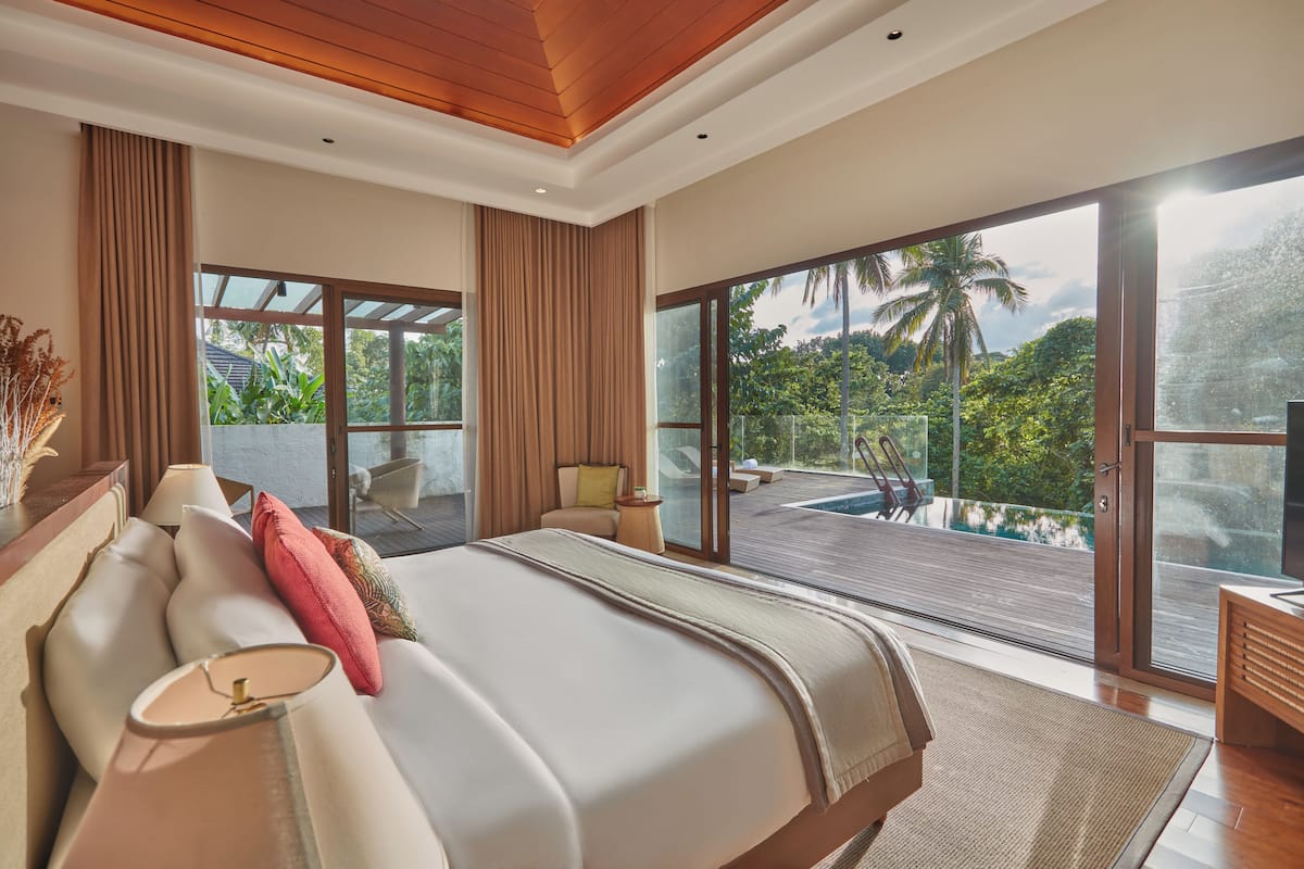 Ein modernes Schlafzimmer mit einem großen Bett, Blick auf einen Pool und einem Balkon.