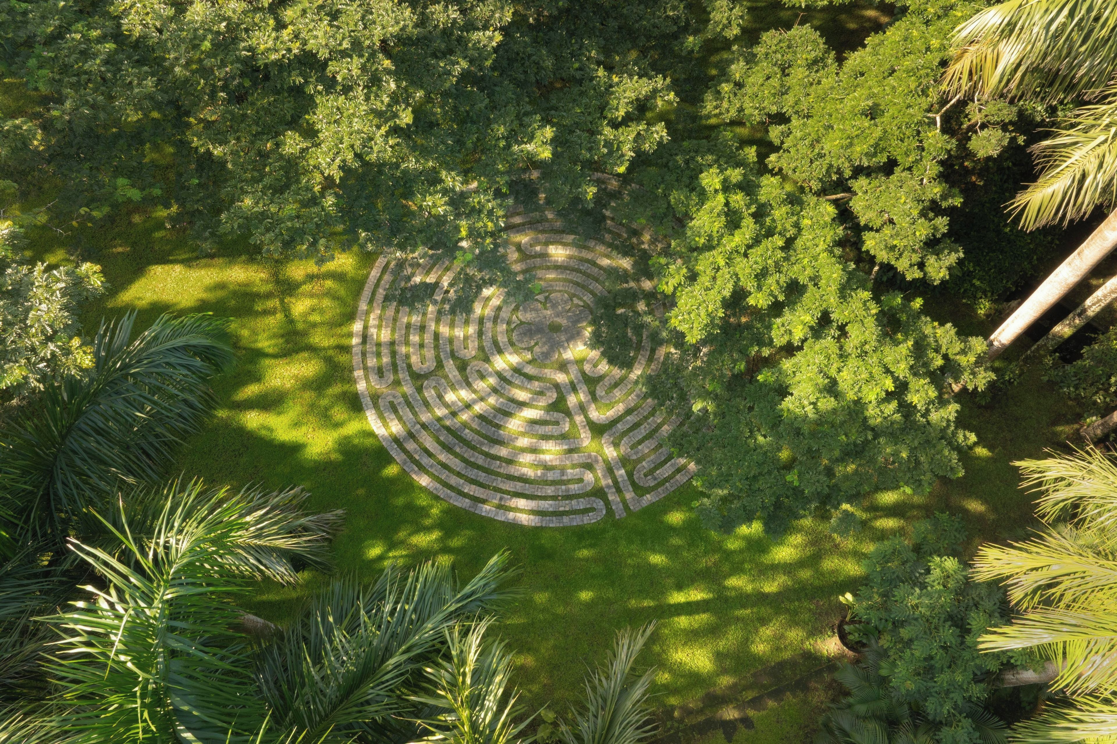 An aerial view of a landscaped area with a circular stone pattern surrounded by dense greenery.