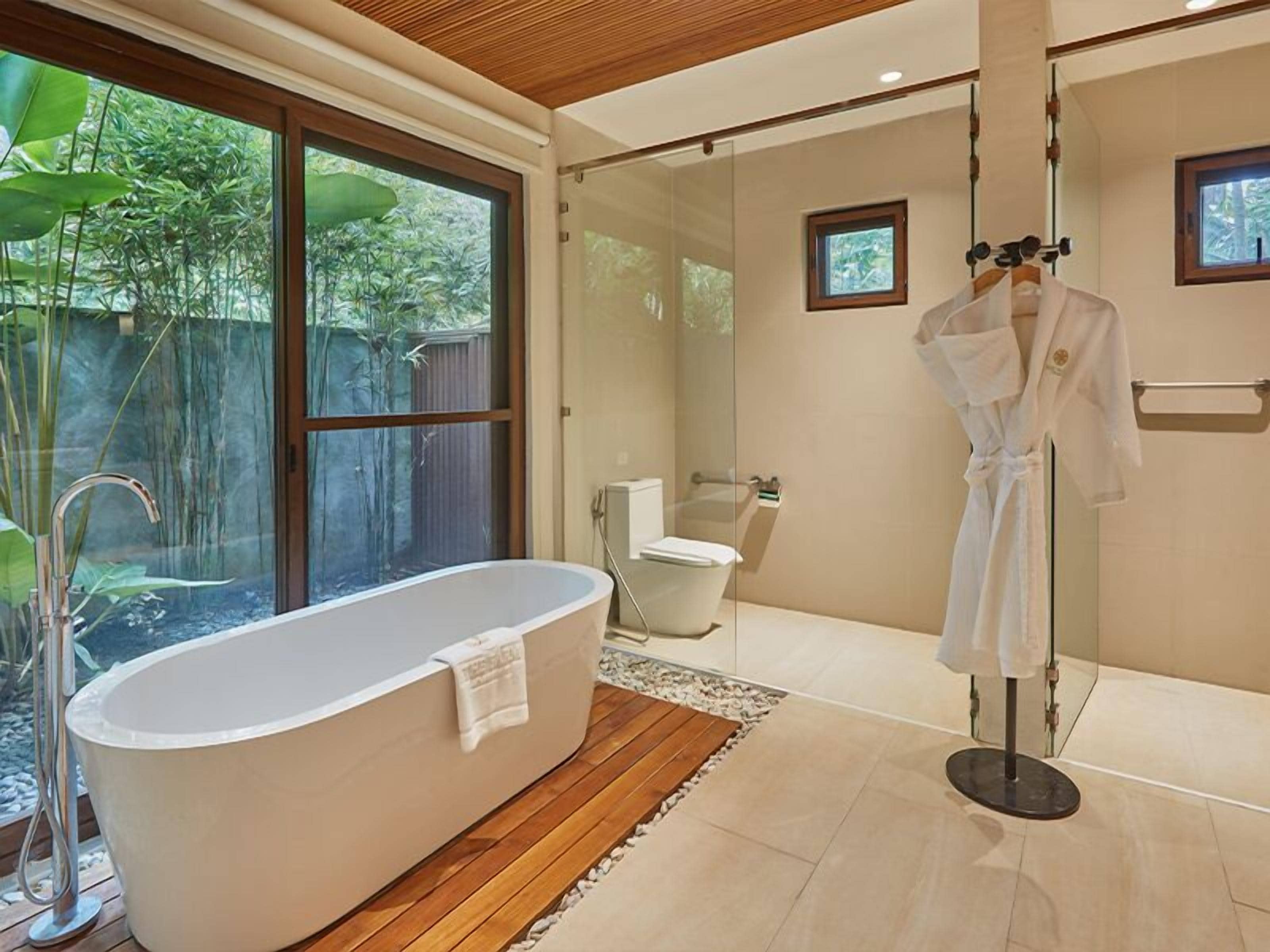 A modern bathroom with a freestanding bathtub, a glass-enclosed shower, and a wooden floor.