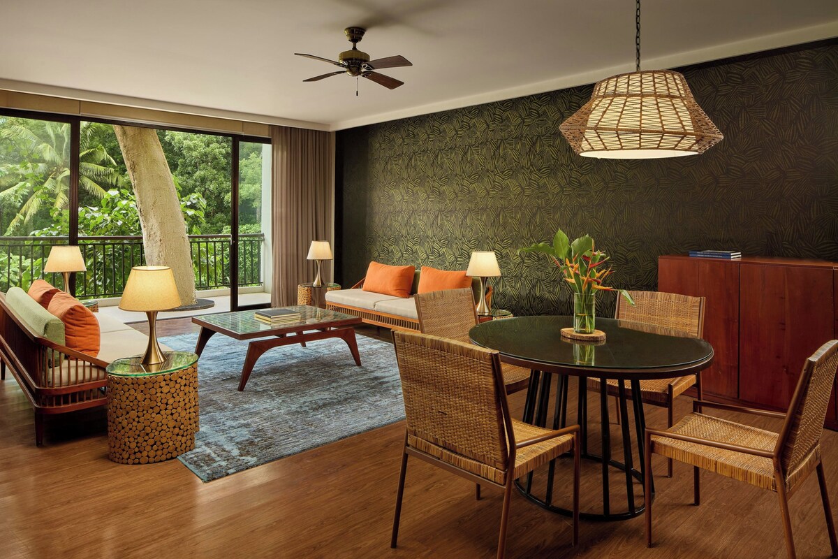 A modern living room with a sofa, chairs, a dining table, and a ceiling fan.