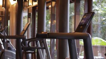 A gym with treadmills, exercise equipment, and large windows allowing natural light.