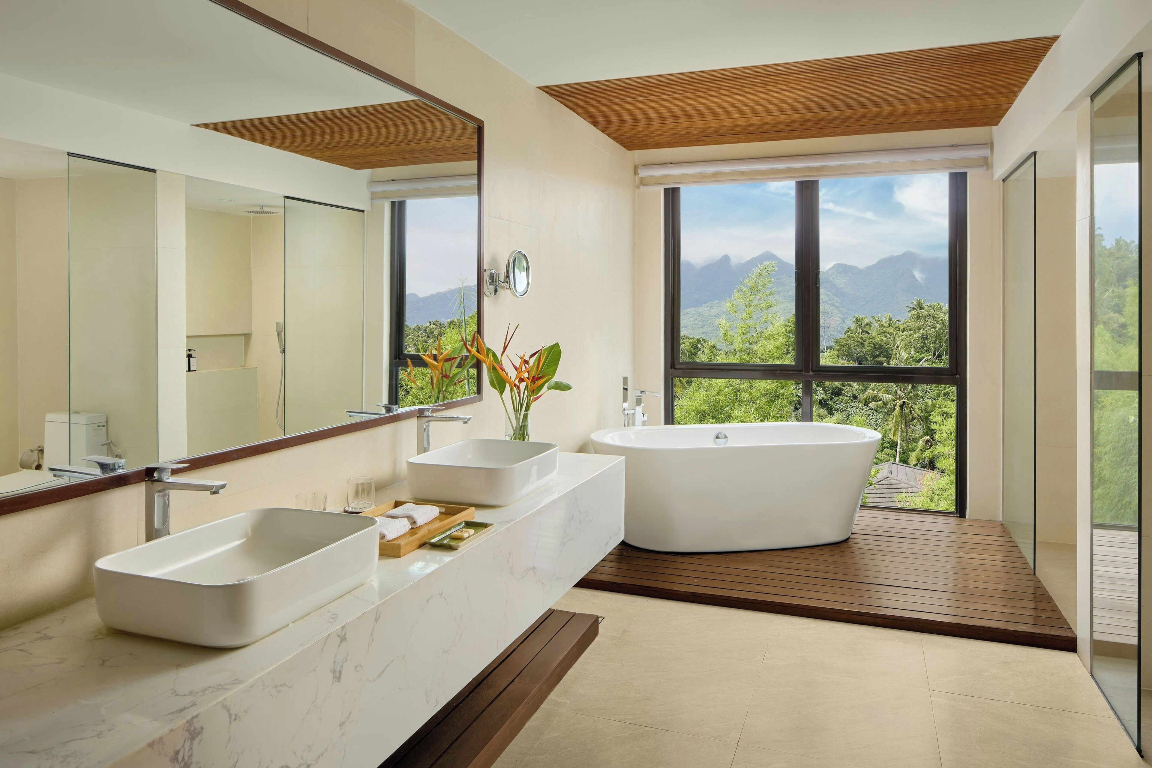 Ein modernes Badezimmer mit einer freistehenden Badewanne, zwei Waschbecken und einem großen Spiegel.