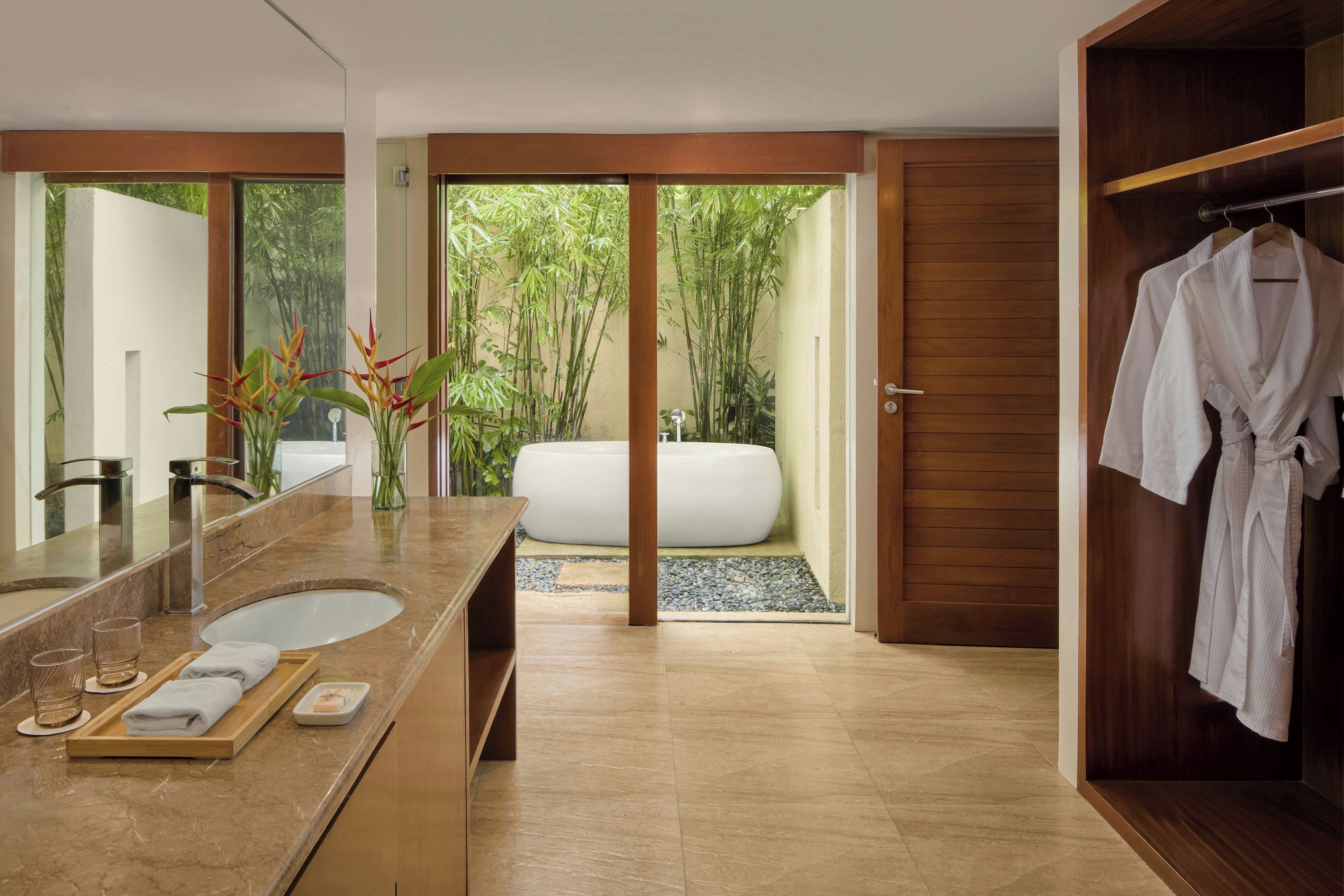 A modern bathroom with a large mirror, a sink, and a bathtub.